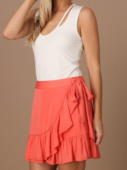 Coral ruffle wrap mini skirt styled with a white tank top.
